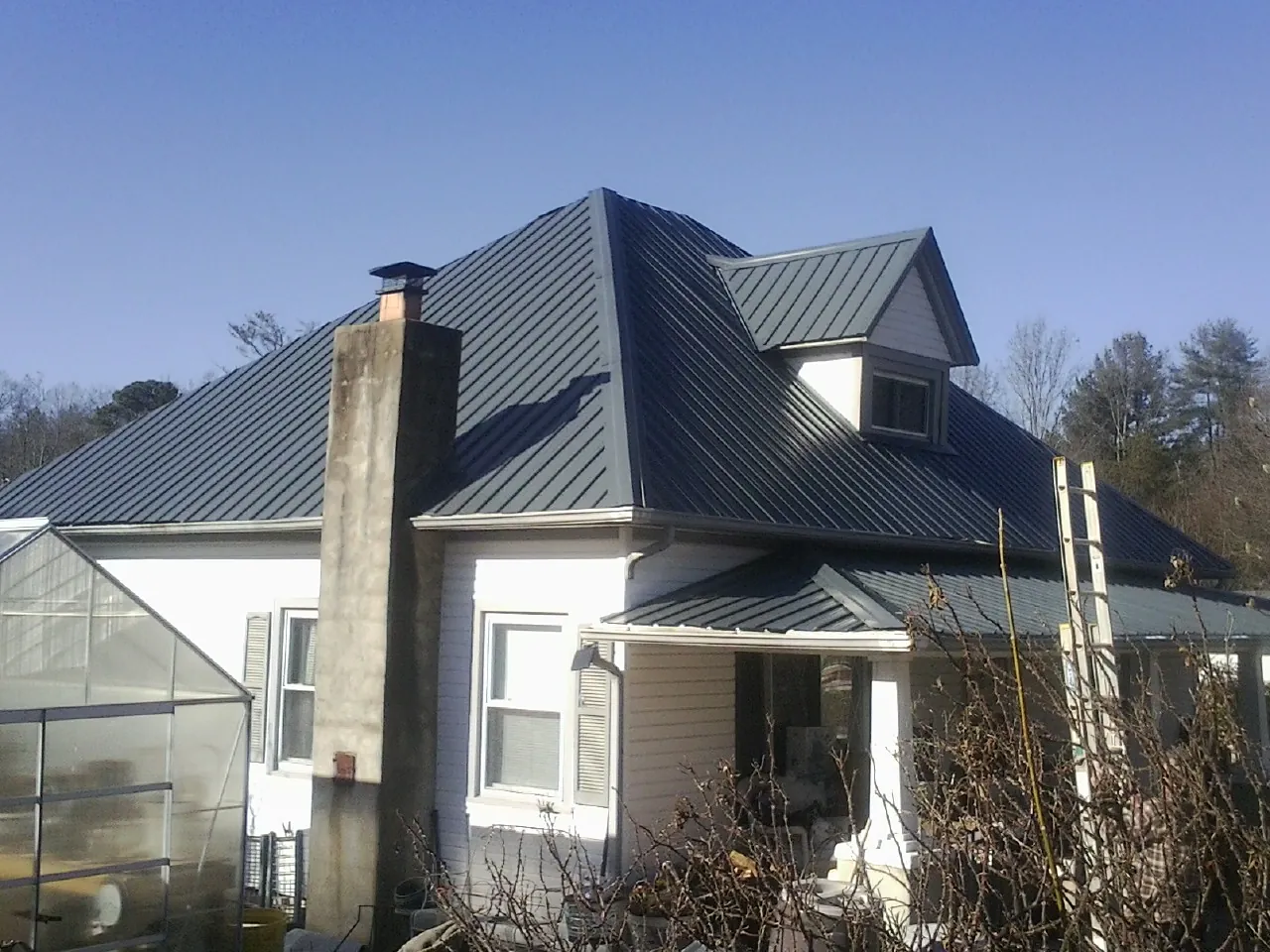 Dark blue standing seam metal roof on a white farmhouse with dormer — Slate & Tile Roof Repair by Roofing Brothers in Toledo
