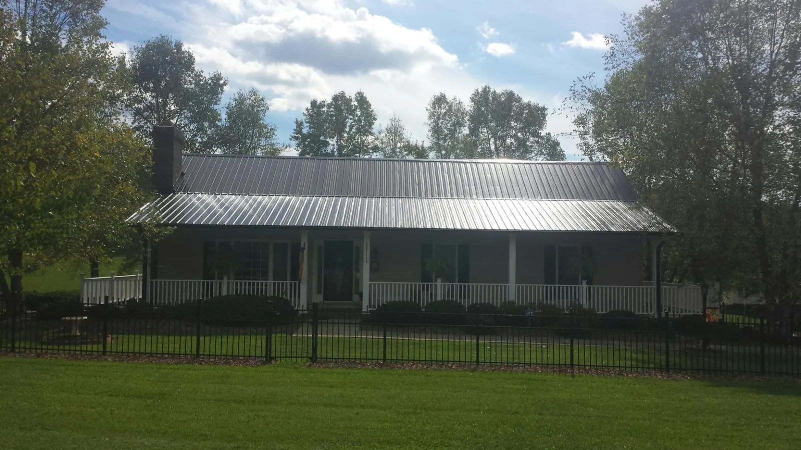 Gray metal roof on a brick ranch with a full width front porch — Gutter Guard Installation work by our crew in Toledo