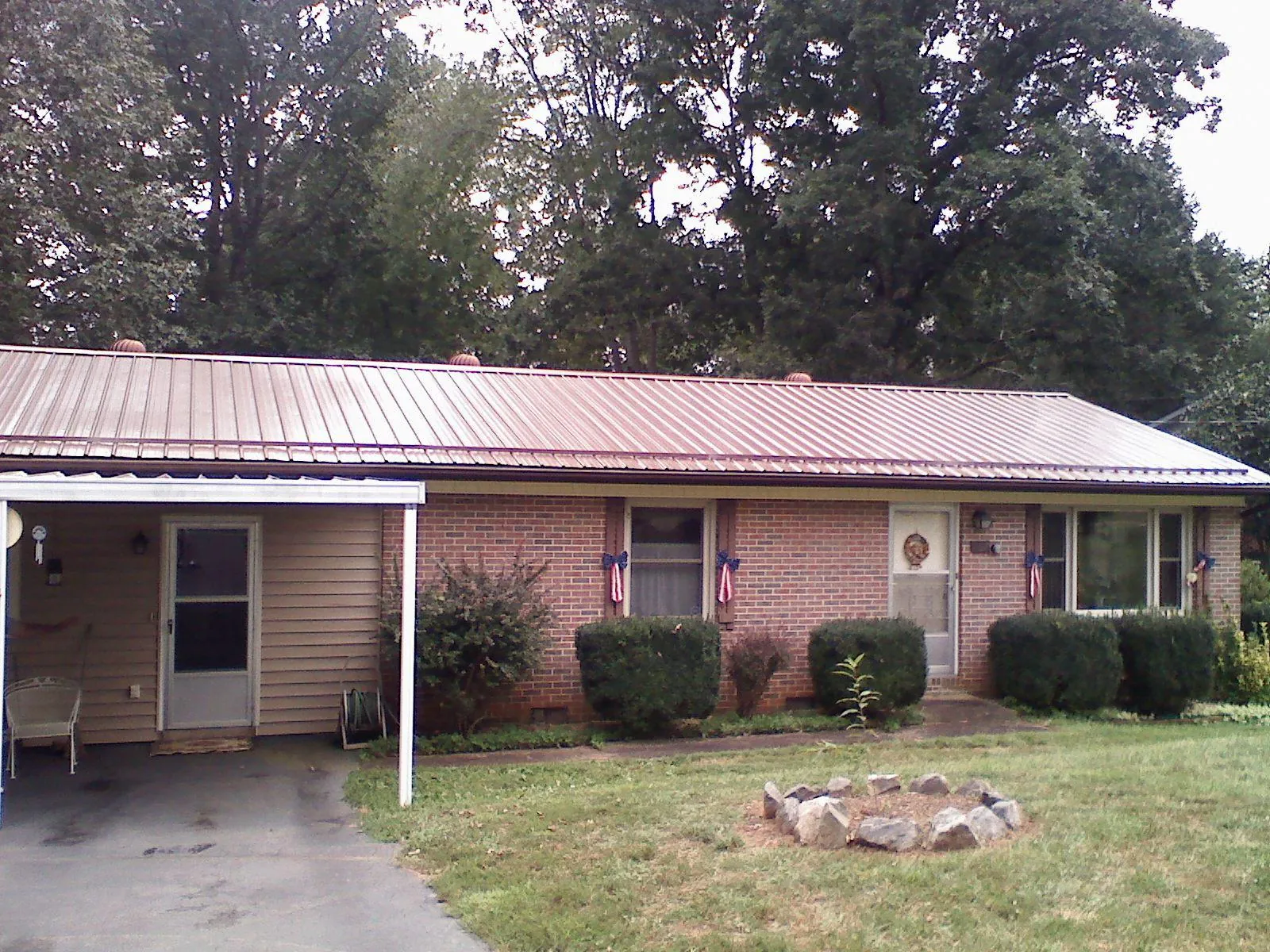 Bronze metal roof and carport on a brick ranch home — Roof Repair work by our crew in Toledo